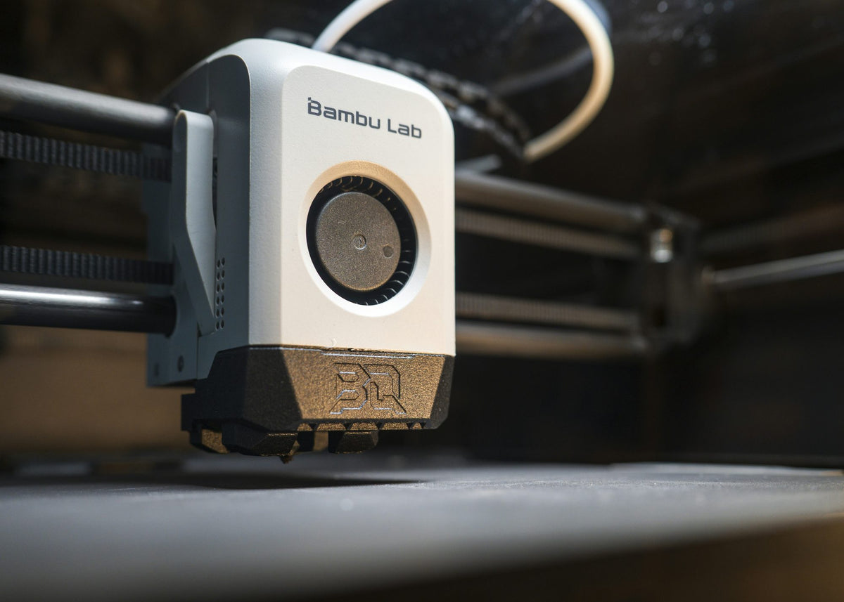 Close-up of a 3D printer print head above the build plate
